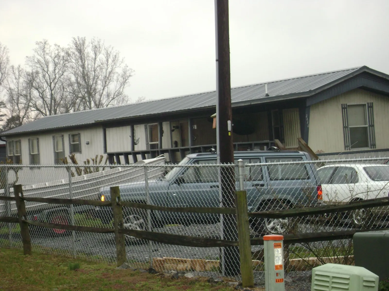 Dark metal roof on a long single story building behind a chain link fence in Brainard
