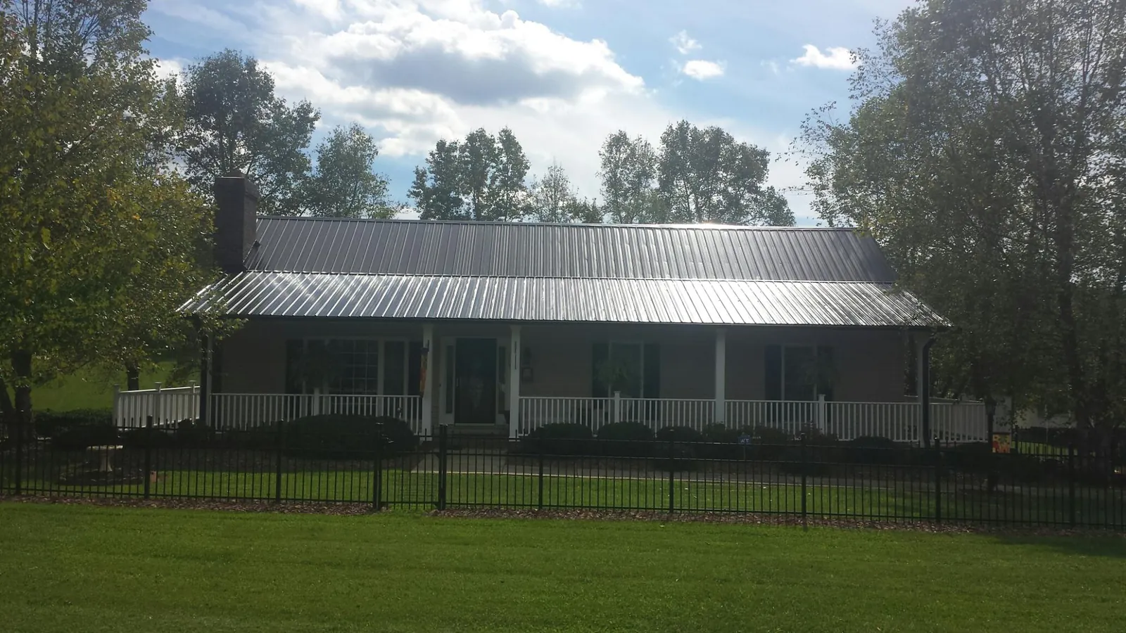 Gray metal roof on a brick ranch with a full width front porch — Gutter Guard Installation work by our crew in Brainard