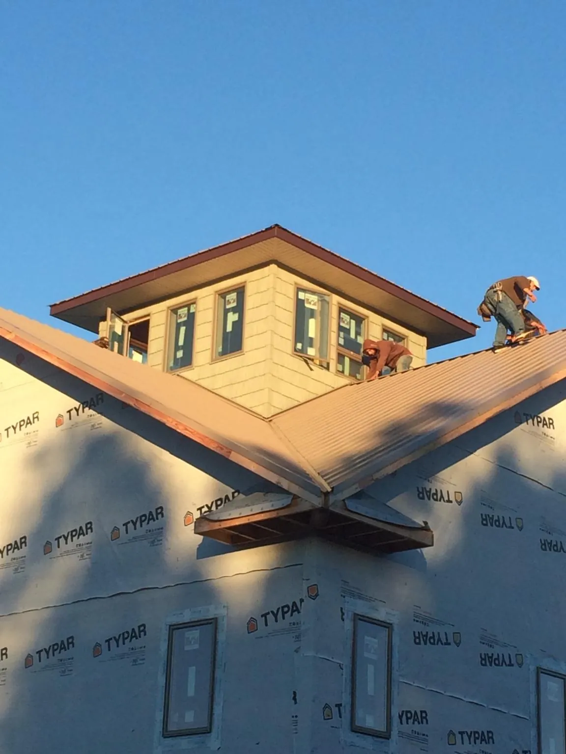 Roofers working around a rooftop cupola on a new metal roof at sunset — Roof Waterproofing in Brainard by Roofing Brothers